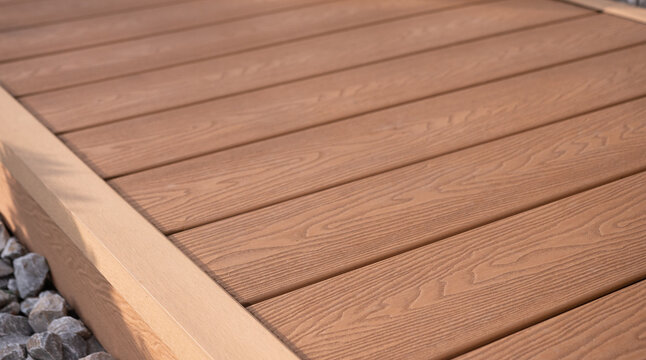 Detail of WPC composite terrace decking with wood texture and corner trim, modern outdoor flooring surface, close-up.