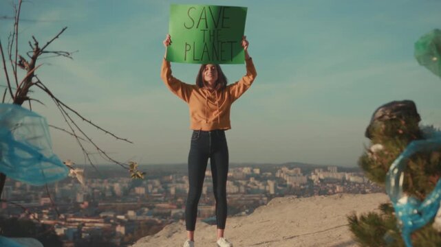 Female protests environment, Young woman presenting green banner atop hill calling for ecological conservation now