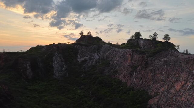Drone footage of Frog Hill in Kubang Semang showing rocky cliffs and sparse vegetation at sunset.