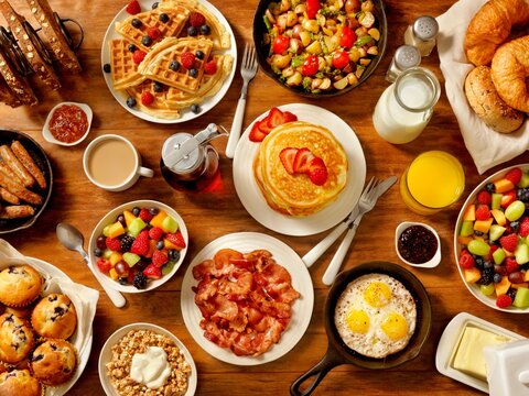 Full English Breakfast Spread with Pancakes Eggs Bacon Sausages Waffles Fruits and Coffee Top View Food Table