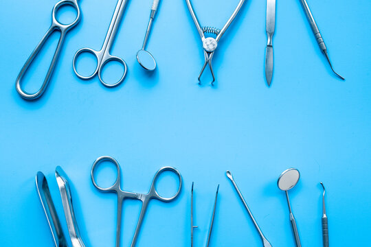 Pattern flat lay of stainless surgical instruments and tools on blue table, top view. Medical background