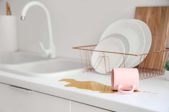Overturned cup and spilled coffee on counter in kitchen