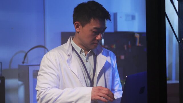 Scientist examines tools carefully, Asian researcher diligently calibrates and tests technological devices in lab