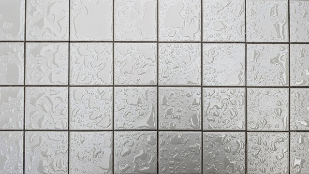 White square ceramic tiles with black grout lines, covered in randomly scattered water drops creating a wet, textured abstract pattern and surface background