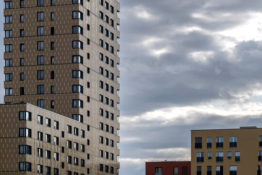 Urban skyline clouds frame modern apartment tower highrise facade as exterior architecture rises over the city in daylight today now