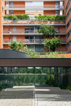 Urban exterior architecture shows modern apartment building facade with terrace greenery and garden spaces that soften the residential structure