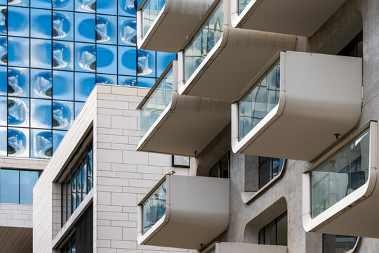 Urban exterior architecture shows modern apartment building facade where glass windows and balcony form a calm residential scene today