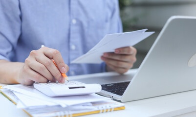 close up man hand press on calculator and check invoice letter from bank  to check about debt and...