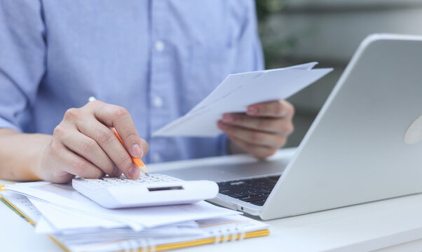 close up man hand press on calculator and check invoice letter from bank  to check about debt and spending monthly for people lifestyle and inflation economic concept