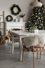 Obraz premium Interior of light dining room with table, fireplace and Christmas tree