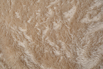 Cozy light brown fluffy fabric textile texture background with soft wavy faux fur material © reddish