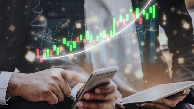 Businessman engaged in financial analysis using smartphone and tablet while stock market graphs display on a digital screen in a modern office atmosphere. Copula