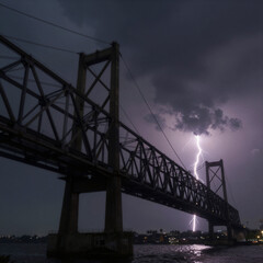 Obraz premium Silhouette of a Steel Cantilever Bridge with Lightning in Stormy Sky