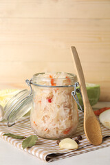 Naklejka na ściany i meble Tasty sauerkraut in jar with ingredients on wooden background