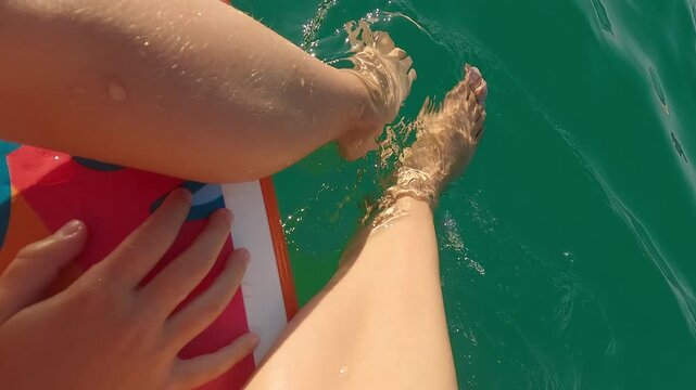 Womens and childrens feet in waves of blue water. Family rides sup on summer sea. Paddleboard. Sup board. Travel vacation holiday