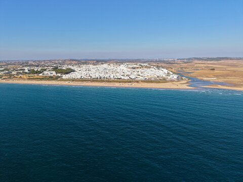 aerial view from the Atlantic Ocean to the beautiful beach Playa los Bateles and the old town in Conil de la Frontera at a sunny summer day, Andalusia, Costa de la Luz, Spain