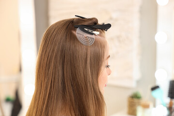 Naklejka premium Young woman getting hair extensions in beauty salon, closeup