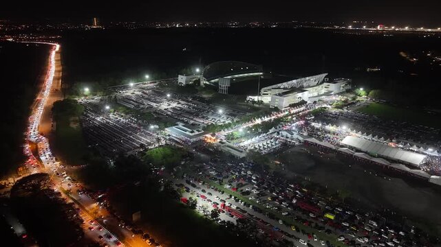 Drone footage of Batu Kawan motorsport festival at night showing stadium, tents, parked cars and traffic.