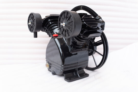 Industrial V-twin cylinder air compressor pump head with black finish, featuring large cooling fans and oil sight glass, professional belt-driven pneumatic component isolated on white.