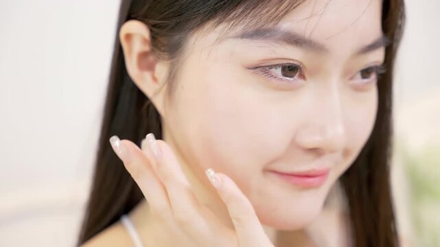 Female woman doing her skincare routine, woman's hands gently pressed patting or massaging a moisturizing lotion or skin care white cream product onto her face, home spa procedures treatment