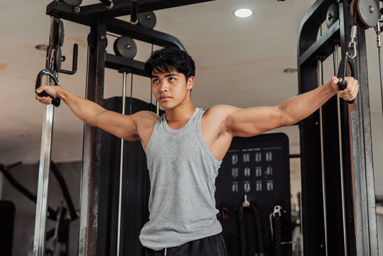 Young Asian man does cable crossover at the gym, focusing on chest development, muscle activation, and controlled movement for upper body strength training.