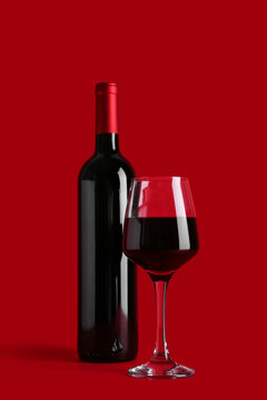 Bottle and glass of red wine on color background
