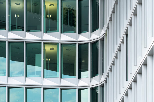 Glass reflection wraps a modern curve corner of an office building facade with windows creating architecture mood and contemporary urban pattern