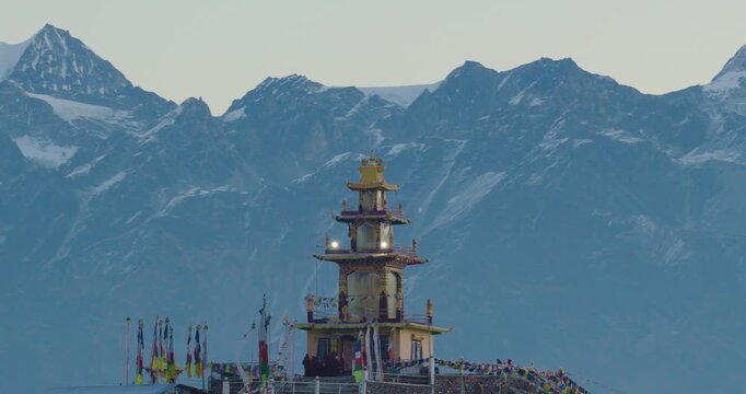 Aerial telephoto shot zooming in on the sacred Ama Yangri Buddhist monument and fluttering prayer flags in Helambu Nepal against the dramatic backdrop of the Gauri Shankar Himalayan range.