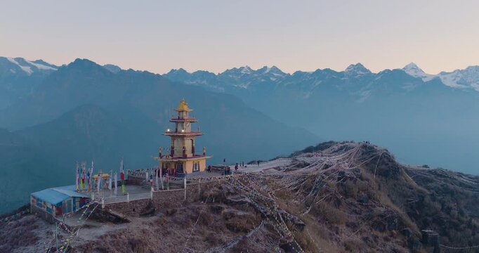 Aerial drone shot capturing the Ama Yangri monument and fluttering prayer flags in Helambu Nepal during a golden sunrise revealing the Langtang and Gauri Shankar mountain ranges.
