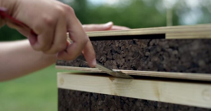 Close up of a metal hive tool being used to pry open the sections of a modern sustainable cork beehive
