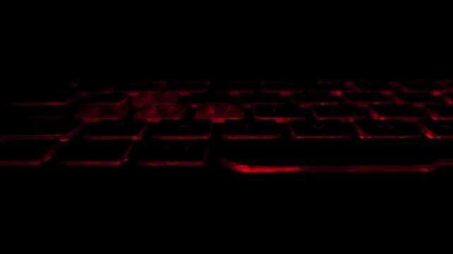 The camera moves smoothly along the multi-colored backlit keyboard in the dark. Gaming, development of AI technology, digital future