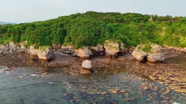 Lateral dolly shot of Golden Pebble Beach cliffs in Dalian, showcasing rugged coastal rock formations and scenic shoreline, ideal for travel, nature and landscape themes.