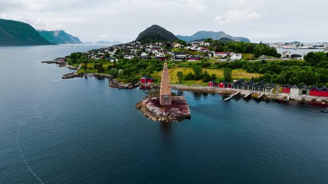 Alesund in Norwegen, Turm f&uuml;r Slinningsbalet. Drohnenflug auf Turm mit Stadt auf einem H&uuml;gel umgeben von gr&auml;sern und B&auml;umen, sowie Bergen im Hintergrund. Sommerliche Stimmung. Establishing shot