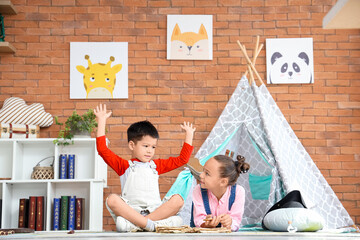 Naklejka premium Cute little children with adventure book at home
