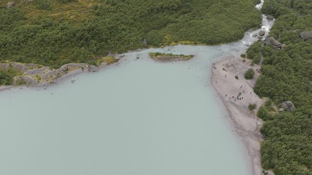 Drohnenflug mit tilt shot &uuml;ber einem Gletschersee mit einem Tal und Wasserf&auml;llen umgeben von verschneiten Berggipfweln bei regenwetter. Raw unbearbeitet