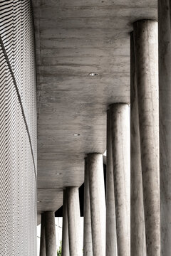 Modern architecture columns in concrete corridor with strong perspective and repetition plus minimal shadows creating monochrome depth