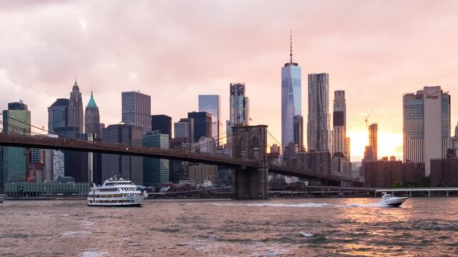 New York, USA. View of Manhattan Bridge and Manhattan in New York, USA at sunset. Colorful cloudy sky with skyscrapers. Sun setting behind the skyscrapers. Time-lapse at sunset