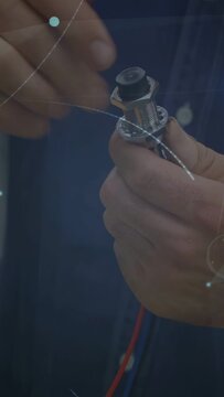 Vertical video: Tech placing lead, securing wire and nut in electronics, ensuring fit amid overlays