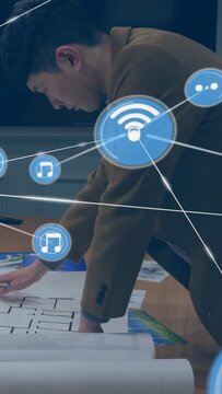 Vertical video: Architect leaning over table marking plan and causing wifi nodes growing and hiding