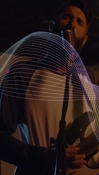 Vertical video: Camera dollying, singer stepping center, playing guitar, waveform boosting vocals