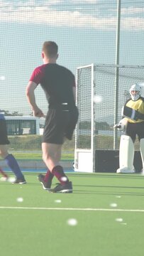Vertical video: Field hockey player sprinting from right dribbling ball into circle trying to score