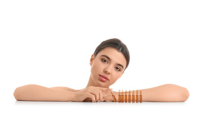 Fototapeta premium Beautiful young woman with ampules on table against white background
