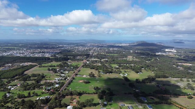 Aerial view of Albany Western Australia, view is looking over the countryside with the city and town in the background. Grass and agricultural feilds, blue cloudy sky with mountains in background