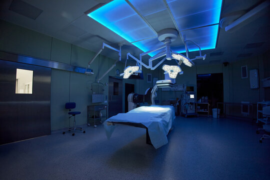 Wide angle shot of empty operating room featuring surgical table and medical equipment, representing hospital readiness and sterile care. Supporting healthcare marketing and clinic promotion