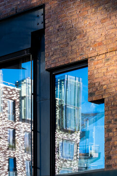 Urban architecture in Oslo blends modern brick windows with glass reflection on a facade as detail hints at city renewal in daylight today