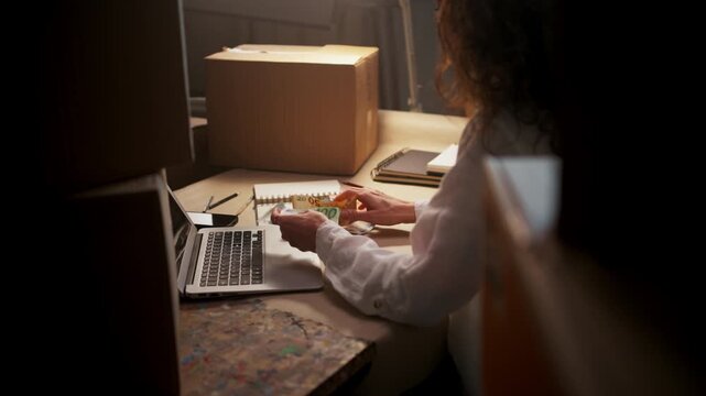 Female Employee Systematically Preparing Shipments And Documenting Financial Activities In Busy Night Setting