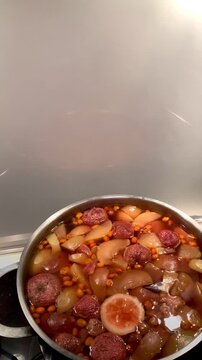 compote is cooked in a saucepan on the stove, apple-strawberry compote in a silver saucepan, opening and closing the lid.  selective focus