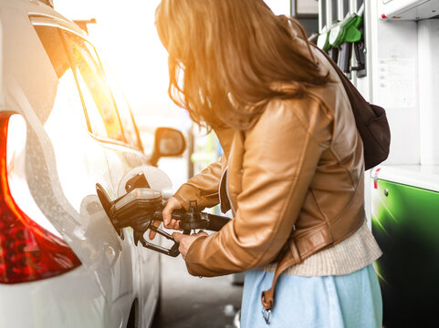 Woman Refuels A Vehicle At A Service Station With Detail Of Driver And Car During Refueling