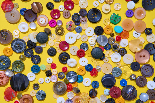 Colorful sewing buttons on bright yellow background