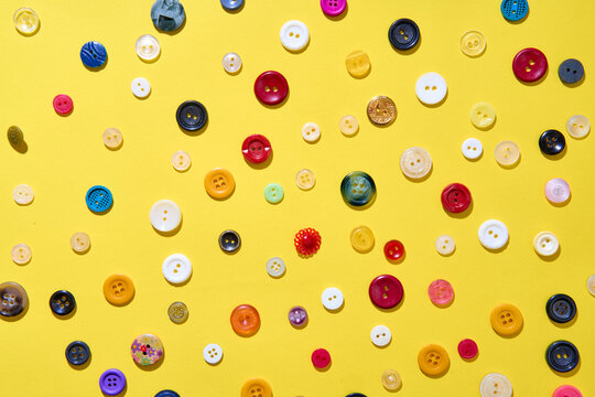 Colorful sewing buttons on bright yellow background
